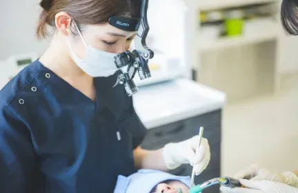 拡大鏡を使って歯周外科治療を行うところ